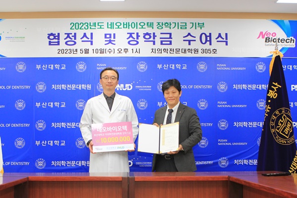 김용덕 부산대 치전원장(좌)이 네오 김거태 본부장에게서 장학금을 전달받고 있다.